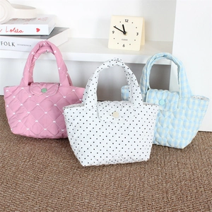 Close-up of quilted mini handbags in pink heart, polka dot, and blue plaid patterns
