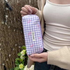Detailed shot of purple checkered pouch with pink bow prints and metal zipper ring