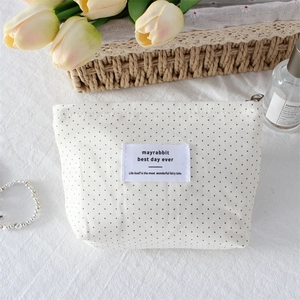 Detailed view of cream polka dot makeup bag with metal zipper and floral decor