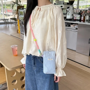 Detailed view of checkered mini phone bag with pink cord strap and snap closure button