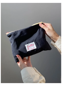 Close-up of black nylon pouch with yellow zipper contrast and white jolly brand label