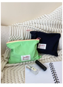 Close-up of portable macaron cosmetic bags in green and navy with contrasting zippers
