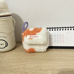 Detail van zacht pluche oortelefoonhoesje met paars koord op een warm bureauoppervlak