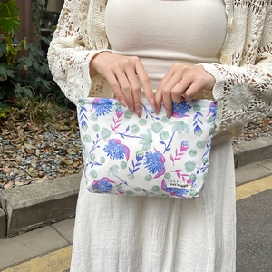 Detailed outdoor shot of a floral canvas makeup bag with blue and pink petal patterns
