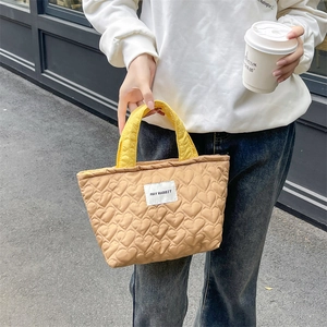 Detailed heart quilted tote bag in camel and yellow with custom brand label outdoors