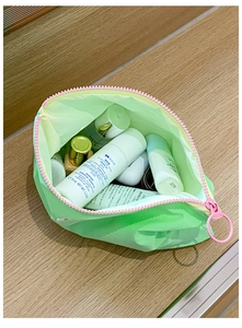 Close-up of mint green makeup bag with pink zipper and round pull on wooden background