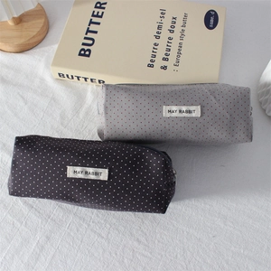 Close-up of polka dot pencil case with MAY RABBIT label on soft fabric surface