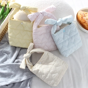 Detailed view of quilted heart pattern bags in pastel colors with bow-shaped handles