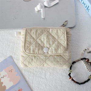 Detail of beige quilted mini pouch with snap button and metal zipper for small storage