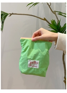 Détail de la pochette en tissu vert avec étiquette Jolly et fermeture éclair colorée