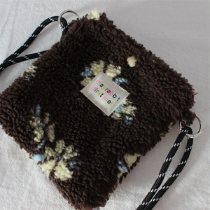 Detail of plush fleece crossbody bag featuring floral jacquard and woven rope strap