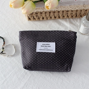 Detailed close-up of polka dot canvas cosmetic bag with woven label and zipper closure