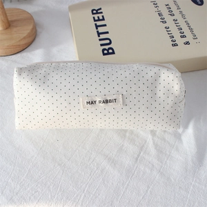 Close-up of canvas pencil case with black polka dots and May Rabbit logo label