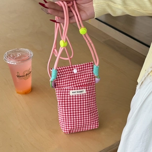 Detail of red gingham phone bag featuring pink woven strap and yellow spherical buckle