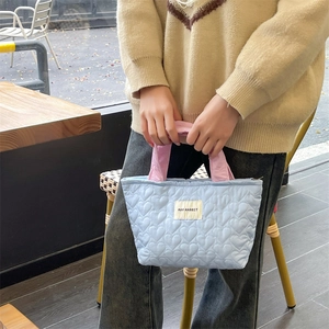 Macro shot of light blue heart-quilted fabric handbag with pink handles and brand tag