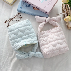 Detail of quilted heart patterns and soft bow-knotted handles on light blue and pink handbags