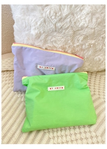 Two small macaron-style cosmetic pouches in purple and neon green with hi jolly tags