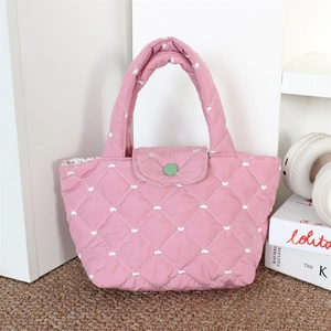 Detail of pink quilted tote bag with heart embroidery and a green button closure
