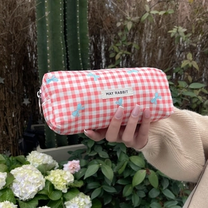 Close-up of red plaid makeup bag with bow print and MAY RABBIT label held by hand