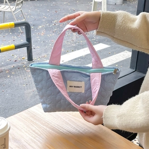 Detailed heart-quilted blue tote bag with contrast pink handles and mint green zipper