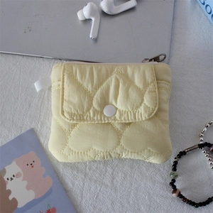 Detail of yellow quilted heart pouch featuring front snap pocket and side loop