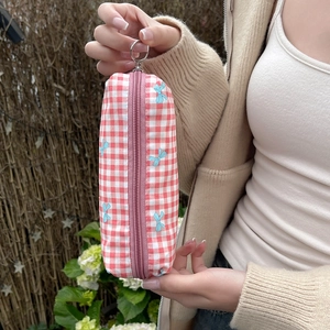 Close-up of red checkered fabric pouch with blue bow prints held by a hand outdoors