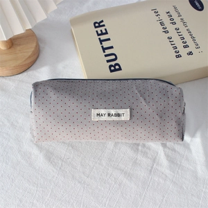 Detailed close-up of a gray polka dot canvas pencil case with zipper and fabric label