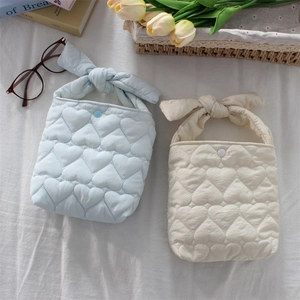 Detail of quilted heart patterns on soft blue and cream handbags with knotted top handles