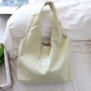 Detail of beige canvas tote bag with black polka dots and mayrabbit fabric label