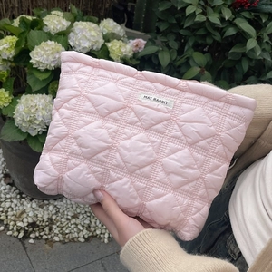 Detailed shot of pink quilted cosmetic bag with May Rabbit label in outdoor garden