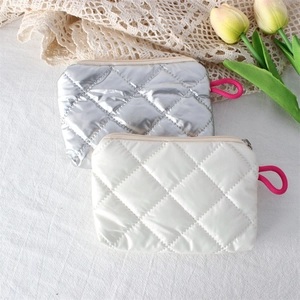 Close-up of quilted rhombic coin purses in silver and white with metal zipper and rope