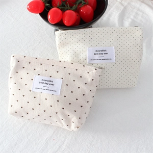 Detailed view of canvas makeup bags featuring brown polka dots and heart patterns