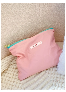 Pink nylon cosmetic bag detail featuring blue zipper and hi jolly woven label