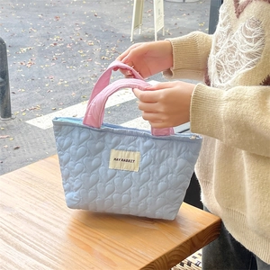 Close-up of heart-shaped quilted pattern and May Rabbit logo on blue handbag
