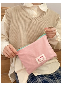 Pink nylon cosmetic pouch with 'jolly' woven label and colorful cord zipper detail