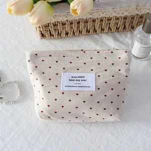 Detailed top view of a canvas makeup bag with red heart pattern on white cloth