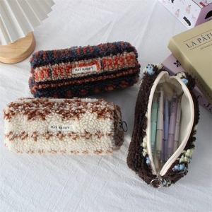 Close-up of soft plush pencil cases with striped patterns and lamb wool texture