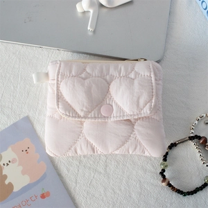 Detail of pink quilted wallet with heart pattern and snap button on textured fabric