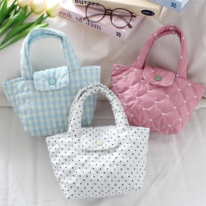 Close-up of quilted cotton handbags with heart patterns and polka dots on a white fabric