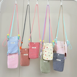 Detailed view of various plaid and polka dot fabric crossbody phone bags on display