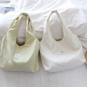 Detailed close-up of light green and beige canvas tote bags with delicate black polka dots