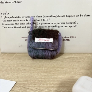 Detail van handgebreid pluche oortelefoonzakje in paars verloop met Mayrabbit-logo