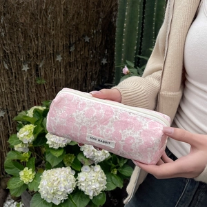 Close-up of floral makeup bag with pink flower pattern and zipper held by hand outdoors