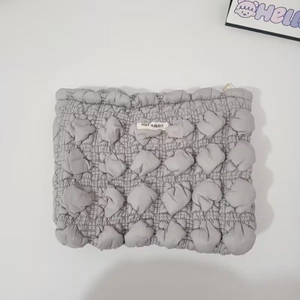 Detail of grey popcorn texture cosmetic bag with metal zipper and logo patch