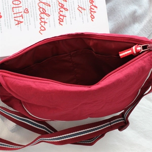 Detail of red dumpling bag interior with slip pocket and striped strap accents