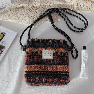 Close-up of plush crossbody bag with colorful geometric patterns and fabric brand label