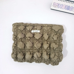 Detail of olive green popcorn fabric texture with MAY RABBIT label on makeup bag