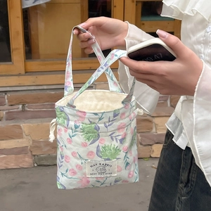 Detail of floral drawstring canvas bag with May Rabbit label on a rustic wooden background