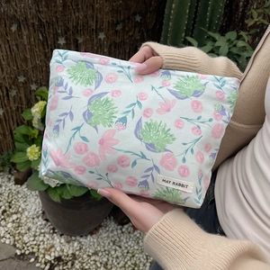 Detailed shot of quilted floral cosmetic bag with May Rabbit label in garden setting