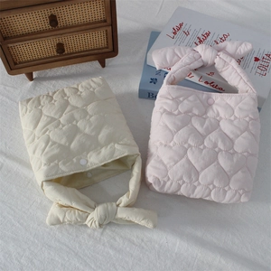 Detail of soft heart-quilted fabric and knotted bow handle on stylish handbags